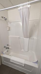 W łazience znajduje się biała wanna z zasłoną prysznicową. w obiekcie Motel Gentilhommière w mieście Saint-Siméon