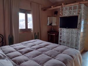 a bedroom with a large bed and a flat screen tv at HOTEL La Quebrada in Río Ceballos