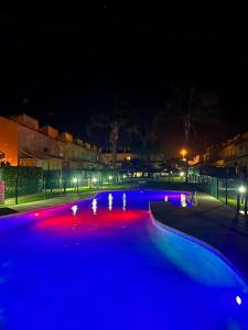 una piscina con luces azules y rojas por la noche en Casa coqueta con jardin, en La Redondela