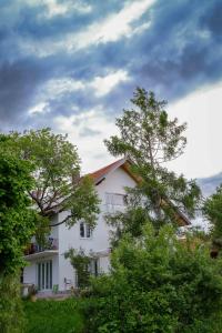ein weißes Haus mit Bäumen davor in der Unterkunft Roger`s Ferienwohnung in Dießen am Ammersee