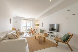 a white living room with a couch and a tv at Paradise bay T3 in São Martinho do Porto