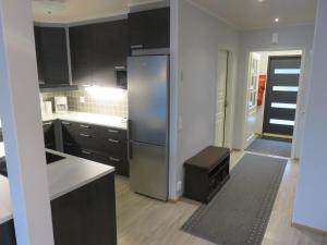 a kitchen with black cabinets and a stainless steel refrigerator at Kotomänty Apartments in Ruka