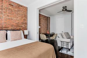 een slaapkamer met een bed en een bakstenen muur bij West Village 2br w wd nr shopping NYC-1274 in New York