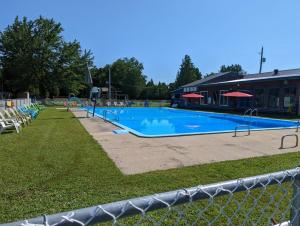 a large swimming pool with chairs and a building at Camping Gaulois - Chalet Vert in Scott