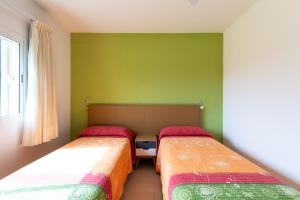 two beds in a small room with green walls at Bungalows Cordial Macaro Beach in Playa del Ingles
