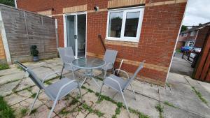 a glass table and chairs in front of a brick building at Lovely 3 Bedroom House in Greater Manchester in Manchester