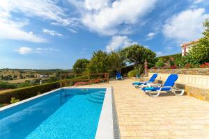a swimming pool with chairs and a table next to a house at Bela casa na Costa Vicentina in Aljezur