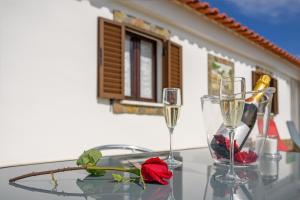 dos copas de champán y una rosa sobre una mesa de cristal en Bela casa na Costa Vicentina, en Aljezur