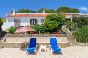 two chairs and an umbrella in front of a house at Bela casa na Costa Vicentina in Aljezur