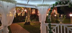 an outdoor wedding ceremony with white curtains and lights at Pałacyk Chojnów in Chojnów