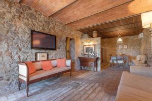 salon z kanapą i telewizorem na kamiennej ścianie w obiekcie Relais Colline San Biagio w mieście Carmignano