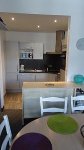 een keuken met een tafel en een aantal witte stoelen bij Appart T4 Luchon plein centre in Luchon +3 foto's