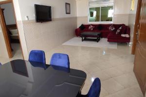 a living room with a table and blue chairs at Logement familial 3 in Selouane
