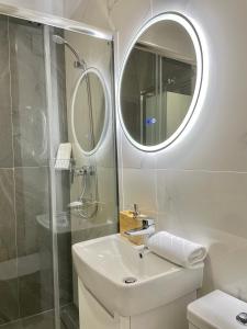 een badkamer met een wastafel, een douche en een spiegel bij Studio No 5 Lebada Lake Residence in Pantelimon