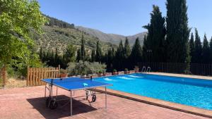 una mesa de ping pong azul junto a una piscina en Finca Rural La Calderera en Valdepeñas de Jaén