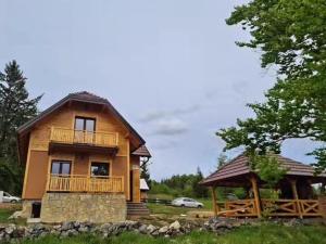 バイナ・バシュタにあるPlaninska kuća Srnaのポーチとバルコニー付きの大きな木造家屋