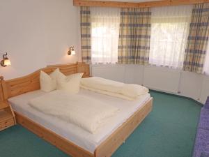 sypialnia z drewnianym łóżkiem i 2 oknami w obiekcie Apartment Diana-3 by Interhome w mieście Pettneu am Arlberg