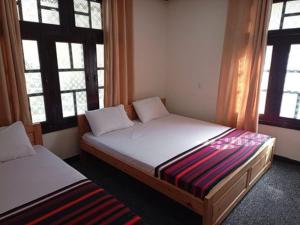a bedroom with two beds and two windows at Hideway Cottage in Chīkīdam