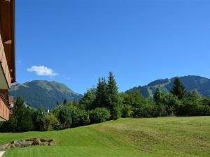 a grassy hill with a house and mountains in the background at Apartment Jacqueline 1 by Interhome in Gstaad