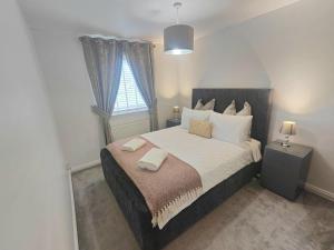 um quarto com uma cama com duas almofadas e uma janela em Lovely 2 Bedroom Modern Ground Floor Flat em Clydebank