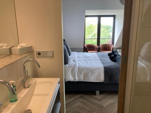 1 dormitorio con cama, ventana y lavamanos en Rue Haute by M&M 4 sterren bed en breakfast vlakbij Maastricht, en Eben-Emael