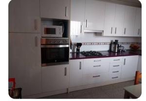 a kitchen with white cabinets and a microwave at La arenera in Algaida