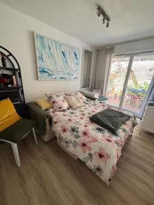 - une chambre avec un lit avec une couette à fleurs et une fenêtre dans l'établissement Studio jardin 5 mn plage Monaco Air Conditioner, à Beausoleil