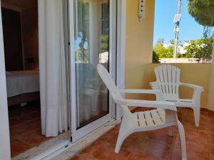 a pair of white chairs sitting on a porch at Aurora Sol in Luz