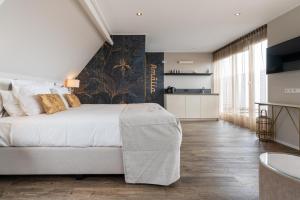 a bedroom with a large white bed and a kitchen at Juuls Domburg in Domburg