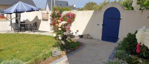 a garden with a blue door and flowers on a wall at Kleines Ferienhaus am Meer in Guissény +4 photos