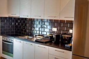 una cocina con armarios blancos y una pared de azulejos negros en Perdika Ionion Villas en Perdika