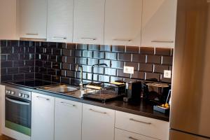 a kitchen with white cabinets and a black tiled wall at Perdika Ionion Villas in Perdika