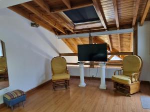 een woonkamer met 2 stoelen en een flatscreen-tv bij Del Bosque - AndarLibre in San Martín de los Andes