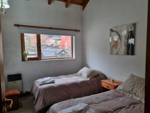 een slaapkamer met 2 bedden en een raam bij Del Bosque - AndarLibre in San Martín de los Andes
