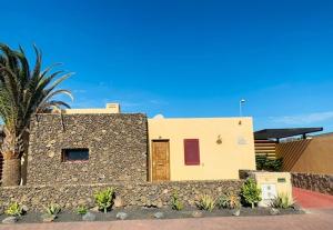 a building with a stone wall next to a palm tree at CASA JAMACO, Corralejo in Corralejo