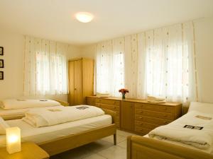 a bedroom with two beds and a dresser and two windows at Apartment Iris A-3 by Interhome in Leukerbad