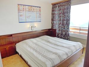 a bed in a room with a window and a bed frame at Apartment Clairière des Barzettes B16 by Interhome in Crans-Montana
