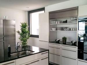 a kitchen with white cabinets and a stainless steel refrigerator at Holiday Home Villa am See 3 by Interhome in Sisikon +26 photos