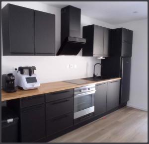 a kitchen with black cabinets and a mixer on a counter at Sur la rive du Lac in Orbey