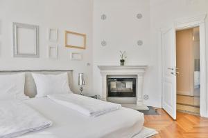 a white bedroom with a bed and a fireplace at Wosching Haus Roemer Living in Merano