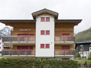 a apartment building with red windows and a balcony at Apartment Snow-Fun B by Interhome in Saas-Fee