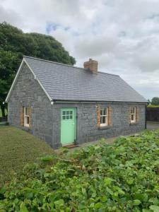 une maison en pierre avec une porte verte dans un champ dans l'établissement Fenniscourt Cottage, à Carlow