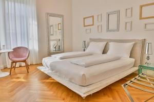 a white bedroom with two beds and a mirror at Wosching Haus Roemer Living in Merano