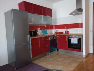 cocina con armarios rojos y nevera de acero inoxidable en Apartmán Rezidence Čertovka 2121 free parking garage en Karlovy Vary