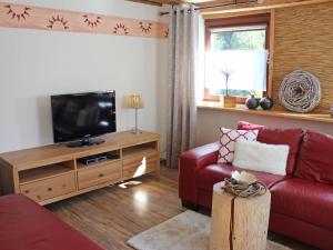 ein Wohnzimmer mit einem roten Sofa und einem Flachbild-TV in der Unterkunft Apartment Ehinger by Interhome in Eisenbach