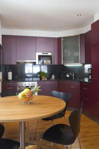 a kitchen with purple cabinets and a wooden table with a bowl of fruit at Apartment Iris B-5 by Interhome in Leukerbad