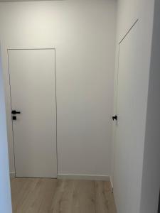 two white doors in a white room with wood floors at BinderHaus 27 in Sibiu