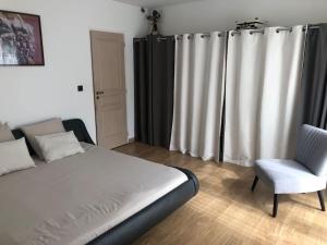 a bedroom with a bed and a chair and curtains at Superbe villa près du Cap d'Agde in Florensac +19 photos