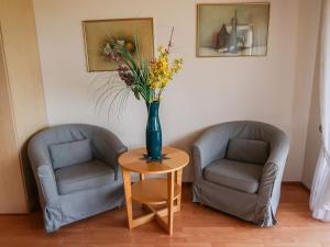 dos sillas y un jarrón con flores en una mesa en Apartment Hoch by Interhome en Neukirch