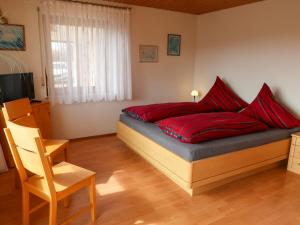 Un dormitorio con una cama con almohadas rojas y una silla en Apartment Hoch by Interhome en Neukirch